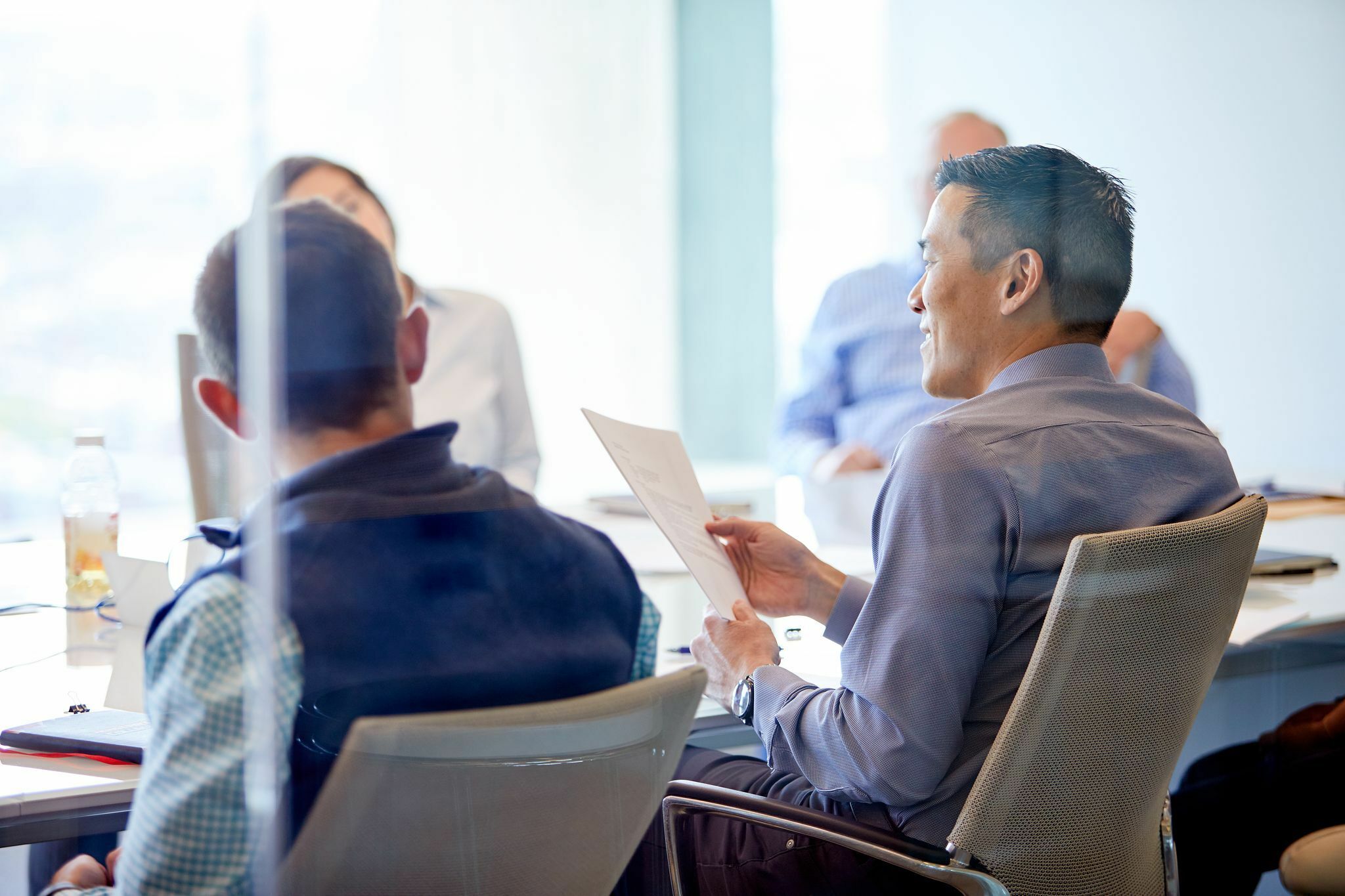 Larry holding a document in a meeting.