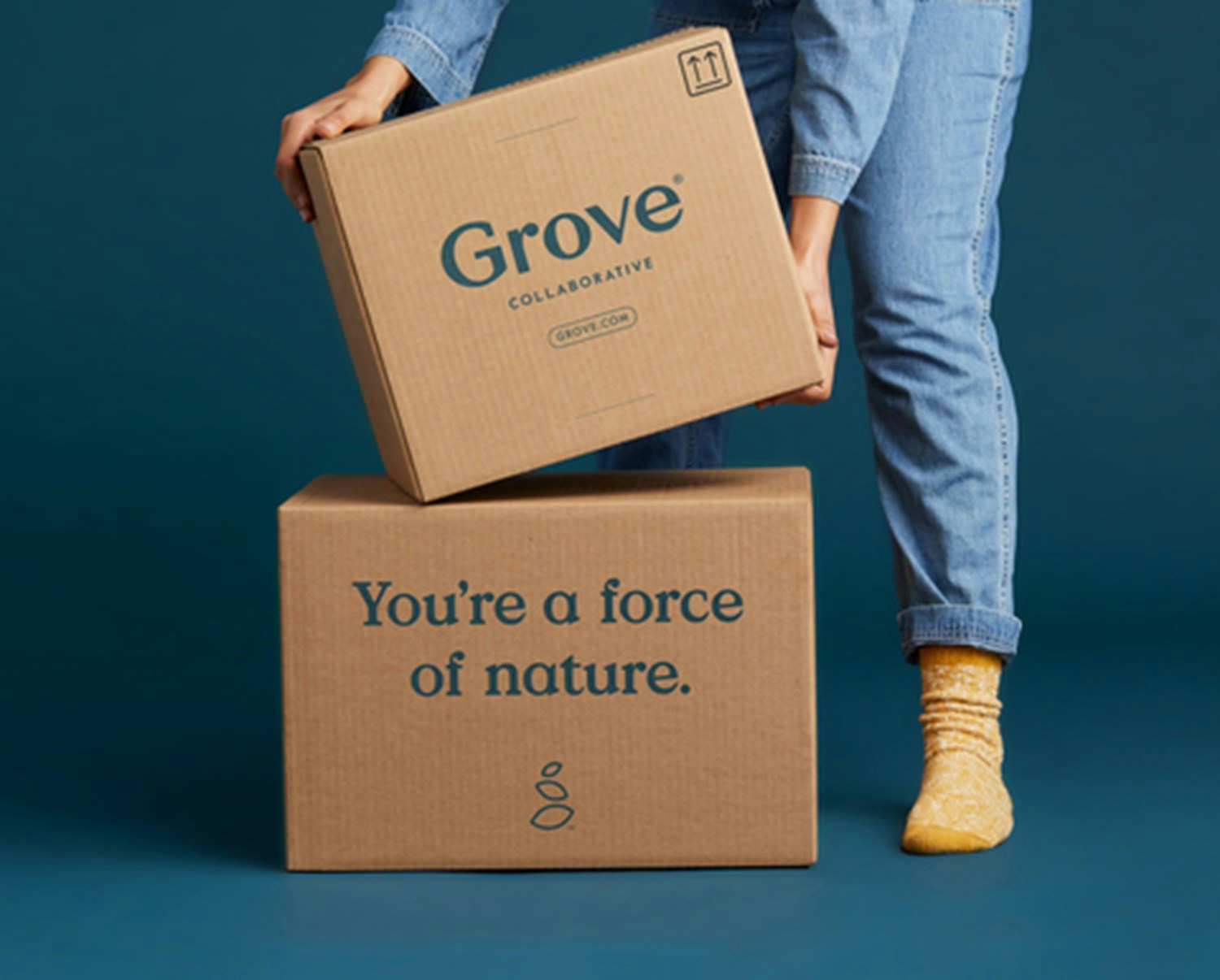 Two Grove Collaborative boxes and a person picking one of them up.