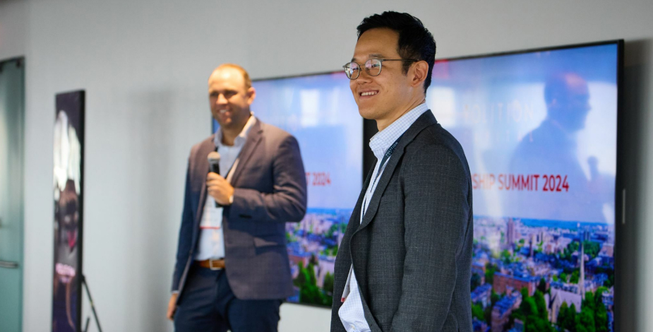 Men presenting onstage during a business conference.